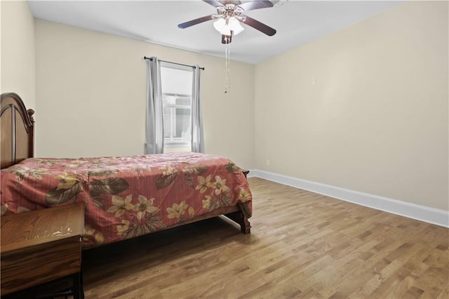 bedroom with ceiling fan, baseboards, and wood finished floors