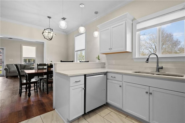 kitchen featuring dishwasher, light countertops, a peninsula, white cabinets, and a sink