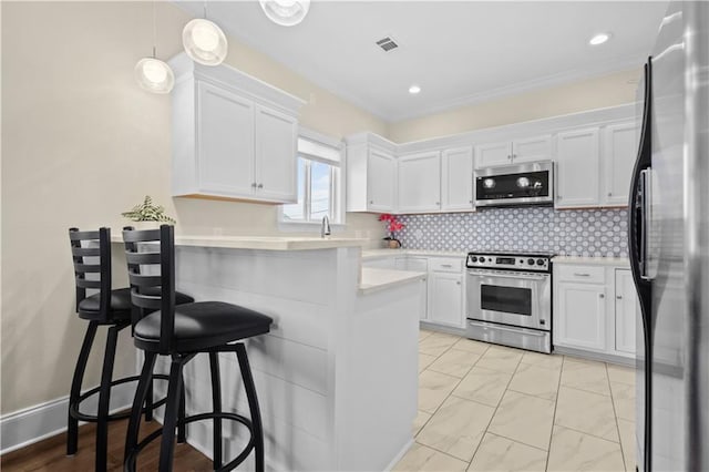 kitchen with visible vents, a breakfast bar, appliances with stainless steel finishes, white cabinets, and light countertops