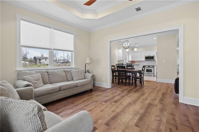 living room with light wood finished floors, visible vents, ceiling fan, and ornamental molding