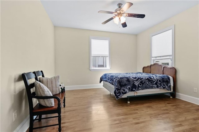 bedroom featuring multiple windows, ceiling fan, baseboards, and wood finished floors