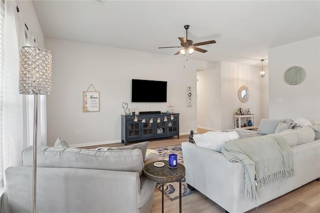 living room with baseboards, light wood-style floors, and a ceiling fan