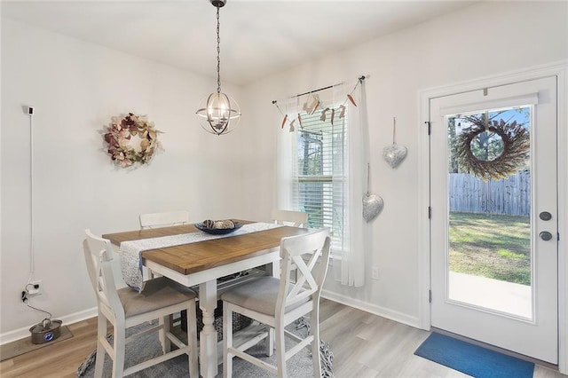 dining area featuring light wood finished floors, an inviting chandelier, and baseboards