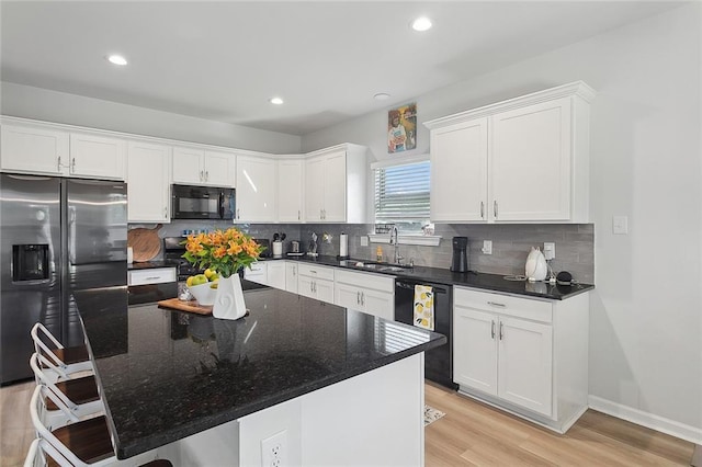 kitchen featuring white cabinetry, black appliances, light wood-style floors, and a sink