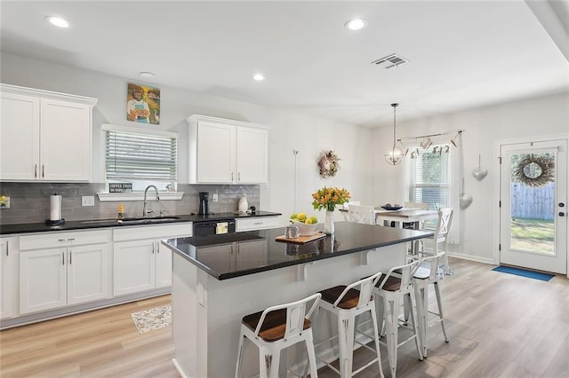 kitchen featuring decorative backsplash, a breakfast bar area, white cabinetry, and a sink