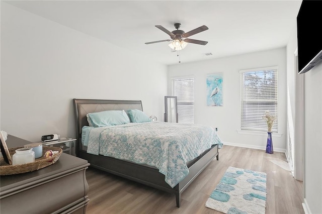 bedroom with visible vents, light wood-style flooring, a ceiling fan, and baseboards