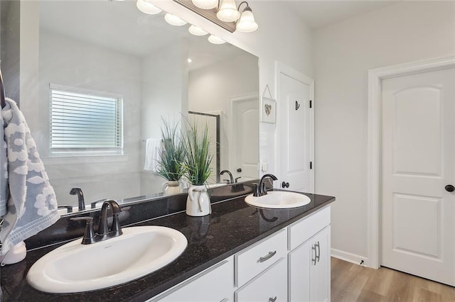 full bathroom featuring double vanity, wood finished floors, a chandelier, and a sink