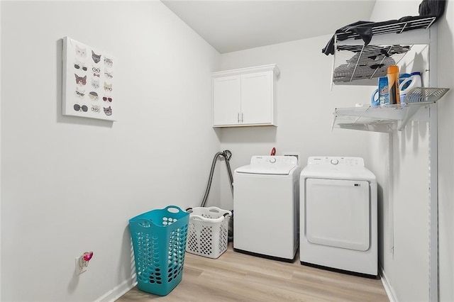 laundry room featuring washer and dryer, cabinet space, light wood-style floors, and baseboards