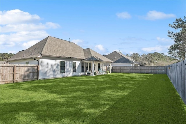 back of property with a shingled roof, a lawn, a fenced backyard, and a patio area