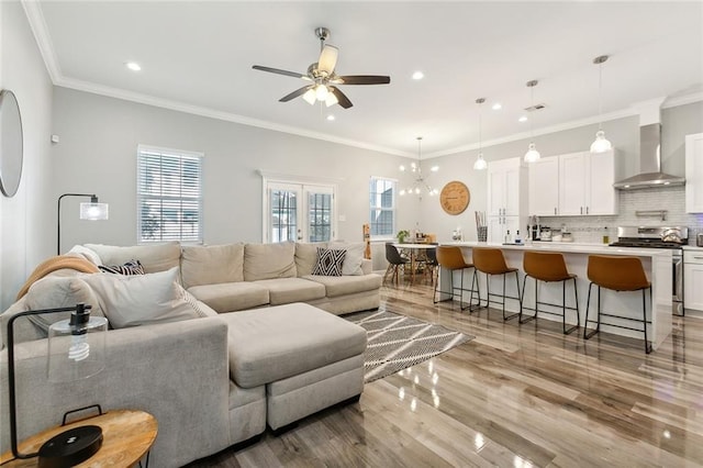 living area featuring recessed lighting, light wood-style flooring, a ceiling fan, and ornamental molding