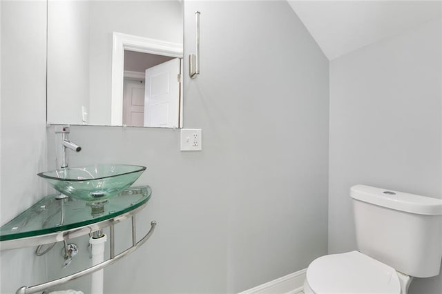 half bathroom with toilet, baseboards, and a sink