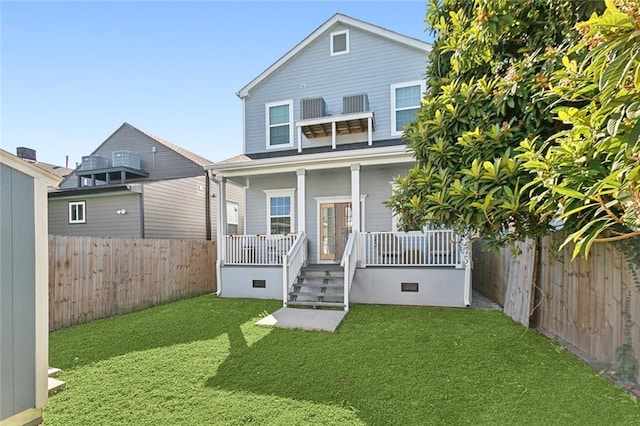 back of house featuring a yard, covered porch, and a fenced backyard