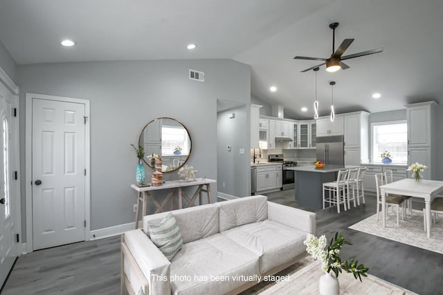 living area with vaulted ceiling, baseboards, visible vents, and dark wood-type flooring