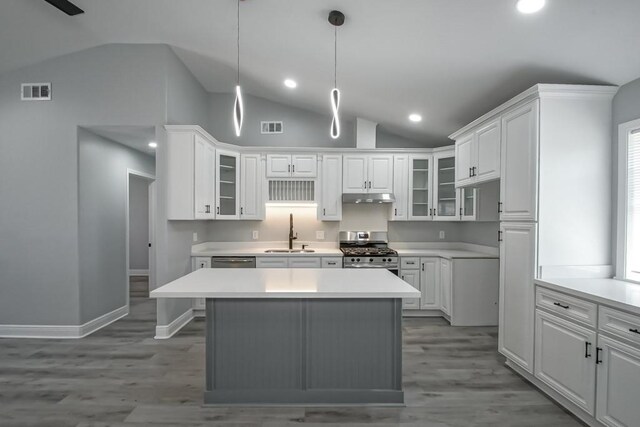 kitchen featuring visible vents, under cabinet range hood, gas range, light countertops, and a sink