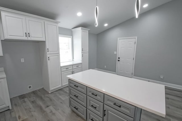 kitchen featuring gray cabinets, light countertops, light wood-style floors, pendant lighting, and white cabinetry