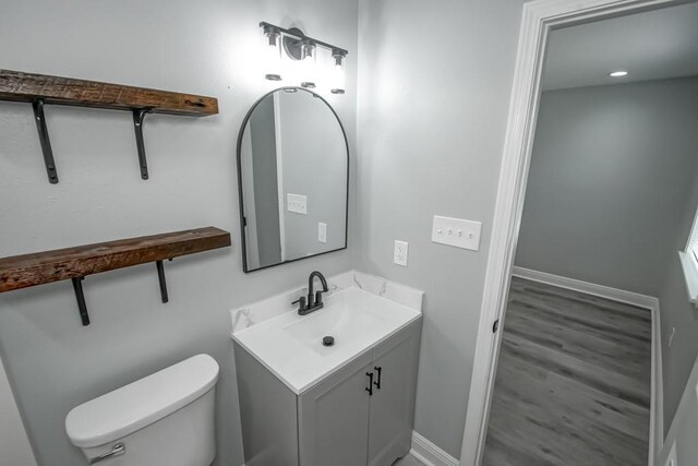 bathroom with toilet, vanity, and baseboards