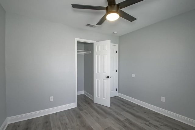 unfurnished bedroom with a ceiling fan, baseboards, visible vents, dark wood-type flooring, and a closet