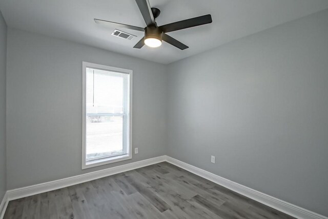 spare room featuring ceiling fan, visible vents, baseboards, and wood finished floors