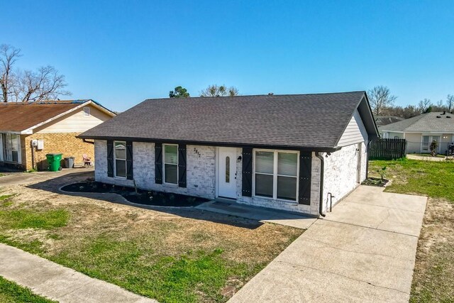 single story home with brick siding, a front lawn, roof with shingles, and fence