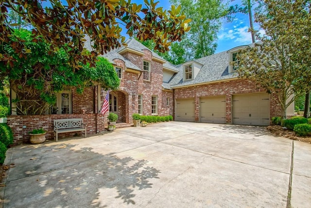 view of front of house with driveway, brick siding, an attached garage, and a shingled roof