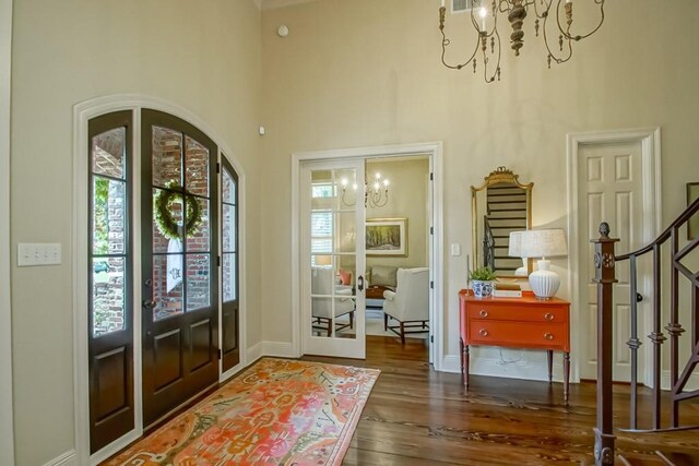 entrance foyer featuring wood finished floors, plenty of natural light, a chandelier, and stairs