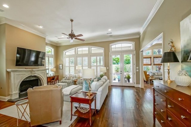 living area featuring dark wood-style floors, plenty of natural light, ceiling fan, and crown molding