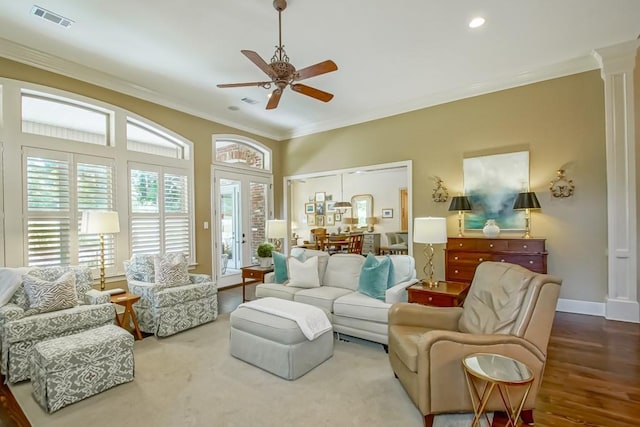 living area featuring visible vents, baseboards, ornamental molding, ornate columns, and a ceiling fan