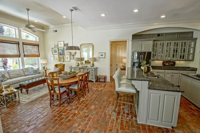 kitchen featuring visible vents, ornamental molding, brick floor, stainless steel refrigerator with ice dispenser, and a sink