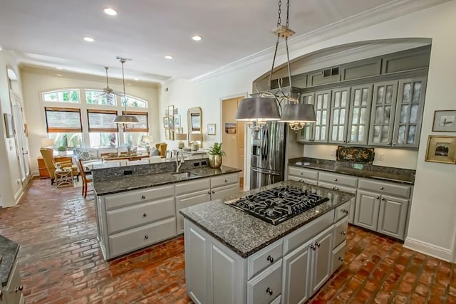 kitchen with a center island, black gas stovetop, brick floor, stainless steel refrigerator with ice dispenser, and a sink