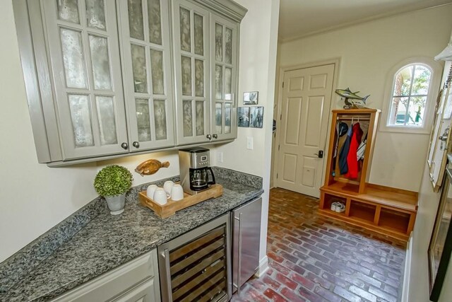 bar featuring beverage cooler, a dry bar, and brick floor