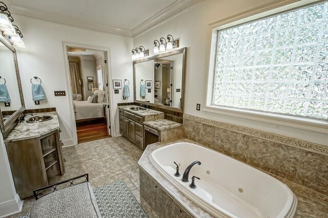 ensuite bathroom with tile patterned floors, ornamental molding, connected bathroom, a tub with jets, and vanity