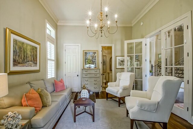 living area with a chandelier, french doors, wood finished floors, and ornamental molding