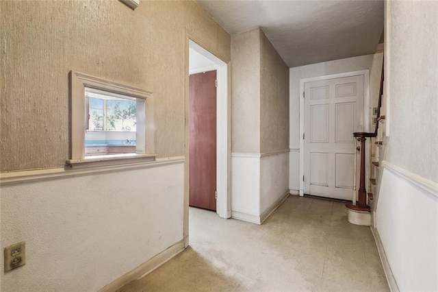 hall featuring stairs, light floors, baseboards, and wainscoting