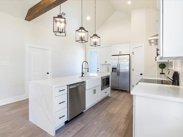 kitchen with light wood finished floors, a kitchen island with sink, a sink, stainless steel appliances, and white cabinetry