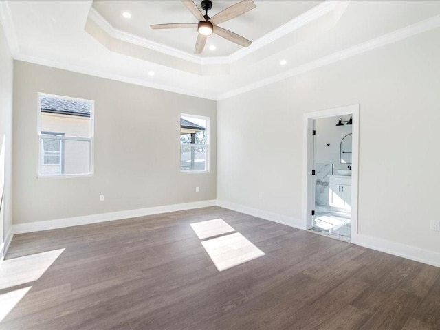 spare room with baseboards, a raised ceiling, wood finished floors, and crown molding