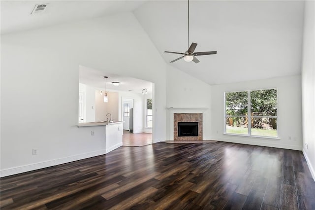 unfurnished living room with dark wood finished floors, a tiled fireplace, visible vents, and a wealth of natural light