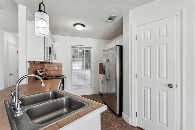 kitchen featuring visible vents, a sink, stainless steel appliances, white cabinets, and backsplash