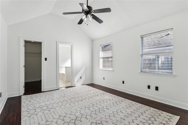 unfurnished bedroom with a spacious closet, baseboards, ceiling fan, dark wood finished floors, and lofted ceiling