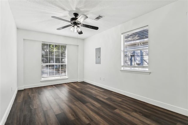 unfurnished room with visible vents, a ceiling fan, electric panel, wood finished floors, and baseboards