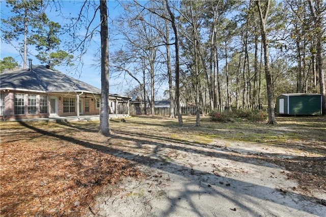 view of yard featuring an outbuilding, a storage shed, and fence