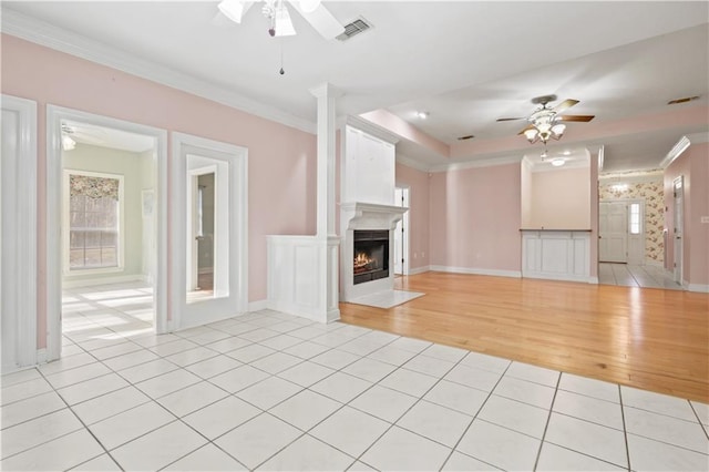 unfurnished living room with visible vents, crown molding, ceiling fan, light tile patterned floors, and plenty of natural light