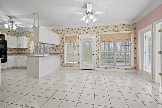 kitchen featuring light tile patterned floors, a peninsula, wallpapered walls, and crown molding