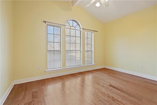 spare room with a ceiling fan, vaulted ceiling with beams, wood finished floors, and baseboards