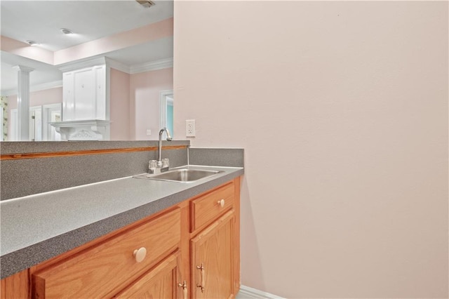 bathroom with crown molding, ornate columns, and a sink