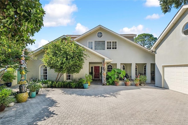 view of front of property with stucco siding, decorative driveway, brick siding, and a garage