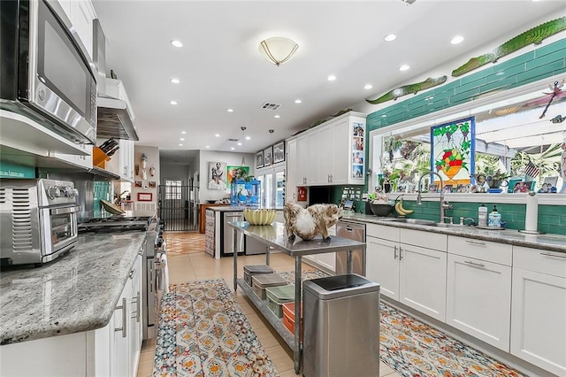 kitchen with visible vents, a toaster, appliances with stainless steel finishes, white cabinetry, and a sink