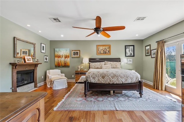 bedroom with recessed lighting, visible vents, a fireplace with flush hearth, and wood finished floors