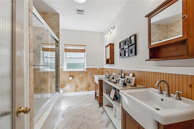 bathroom featuring visible vents, a tile shower, wainscoting, tile patterned floors, and vanity