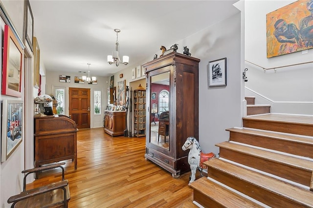 entrance foyer featuring a notable chandelier, light wood-type flooring, and stairs