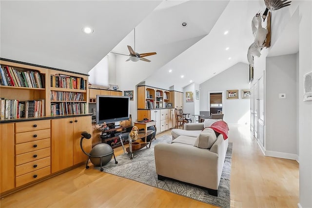 living area featuring light wood finished floors, baseboards, high vaulted ceiling, and ceiling fan